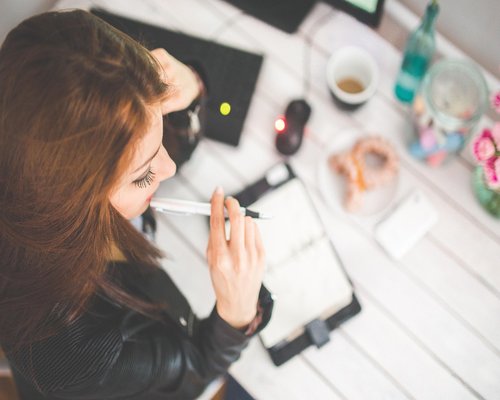 A closed notebook with a pen lying on top of it on a clean desk