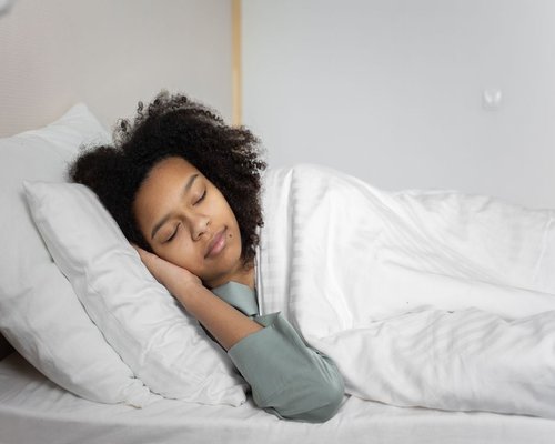 A person sleeping peacefully in a comfortable modern bed with soft lighting